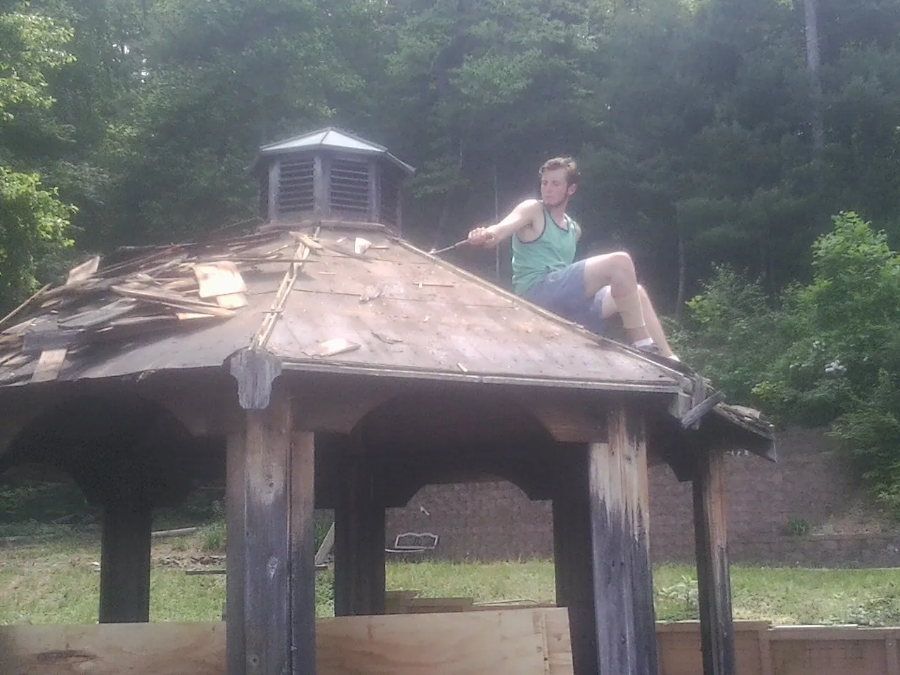 Tearing the old roof off a wooden gazebo before new shakes in Union